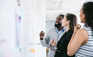 Three people looking at a whiteboard